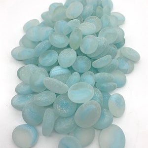 May include: A pile of light blue glass pebbles. The pebbles are smooth and have a frosted finish.