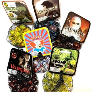May include: A set of 10 bags of marbles with colorful glass marbles. Each bag has a different character on the front, including a werewolf, a mummy, a swamp thing, a triceratops, a vampire, and a clown. The bags are made of a black mesh material.