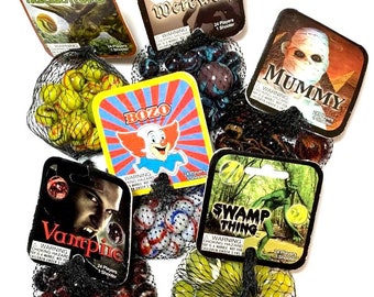 May include: A set of 10 bags of marbles with colorful glass marbles. Each bag has a different character on the front, including a werewolf, a mummy, a swamp thing, a triceratops, a vampire, and a clown. The bags are made of a black mesh material.