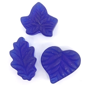 May include: Three blue glass leaf-shaped beads. The beads are in the shape of a heart, an oak leaf, and an ivy leaf.