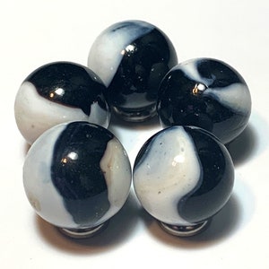 May include: Five vintage marbles with a swirl pattern of black and white. The marbles are arranged in a circular pattern, each with a glossy finish. The black and white design creates a striking contrast, highlighting the classic toy.