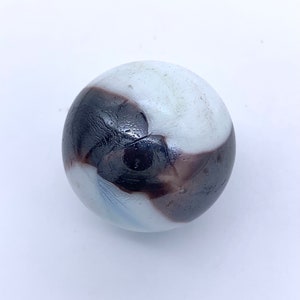 May include: A white and brown glass marble with swirling patterns.