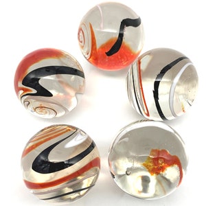 May include: Five glass marbles with swirling patterns of black, white, and orange. The marbles are clear and have a glossy finish.