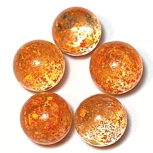 May include: Five orange glass marbles with a speckled, white and yellow pattern.