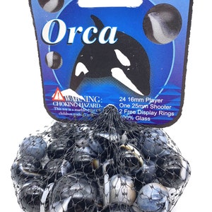 May include: A bag of 24 black and white glass marbles with a blue and white label that says "Orca" and includes the text "24 16mm Player, One 25mm Shooter, 2 Free Display Rings, 100% Glass".