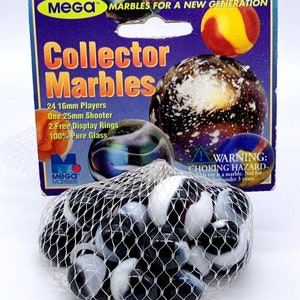 May include: A bag of 24 black and white marbles with a blue and green iridescent marble in the background. The bag is labeled "Mega Marbles for a New Generation" and "Collector Marbles". The bag also includes the text "24 16mm Players, One 25mm Shooter, 2 Free Display Rings, 100% Pure Glass".
