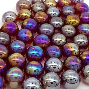 May include: A group of iridescent glass marbles in shades of purple, blue, gold, and silver. The marbles are arranged in a triangular pattern.