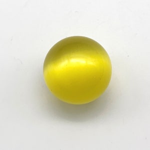 May include: A smooth, round, yellow cat's eye gemstone.