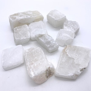 May include: A collection of white selenite crystals of various shapes and sizes. The crystals are smooth and have a translucent appearance.