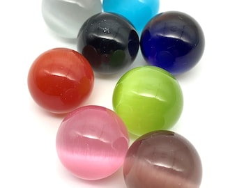 May include: Eight colorful glass marbles in various colors including red, green, blue, pink, purple, black, gray, and brown.