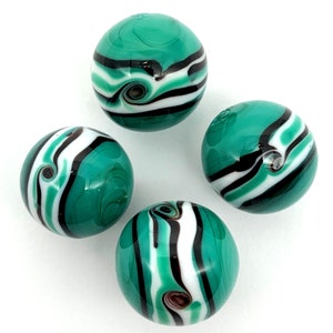 May include: Four green glass marbles with white and black stripes. The marbles have a swirling pattern.