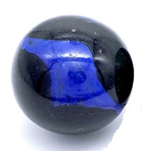 May include: A black and blue glass marble with a swirl pattern. The marble has a dark blue center and a black outer ring.