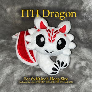 May include: A white plush dragon with red detailing on the wings and head. The dragon has large black eyes and is designed for a 15.24 x 25.4 cm hoop size. The image includes the text "ITH Dragon".