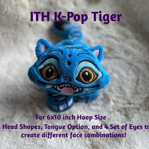 May include: A blue plush tiger with embroidered features, including large eyes and a smiling mouth. The text "ITH K-Pop Tiger" is at the top. The image also includes text about head shapes, tongue options, and eye sets.