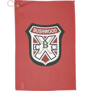 Puede incluir: Toalla de golf roja con un logotipo verde y blanco que dice "Bushwood" y "CBC" con palos de golf cruzados.