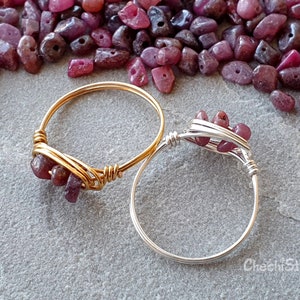 May include: Two wire wrapped rings with pink gemstones. The ring on the left is gold and the ring on the right is silver.