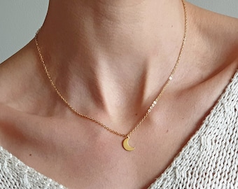 Delicado collar dorado con forma de luna creciente, ideal para combinar con otras joyas.