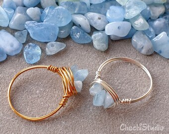 Puede incluir: Dos anillos con piedras de aguamarina envueltas en alambre. Un anillo es de oro y el otro de plata.