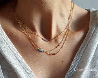 May include: A layered gold chain necklace with small turquoise and purple beads.