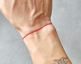 Puede incluir: Un brazalete de cuerda roja usado en la muñeca.