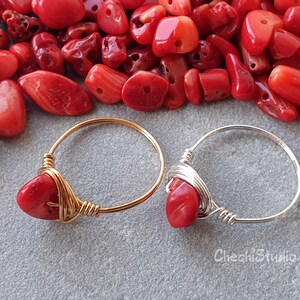 Puede incluir: Dos anillos envueltos en alambre con piedras de coral rojo. El anillo de la izquierda tiene una banda dorada y el anillo de la derecha tiene una banda plateada.