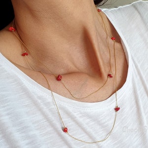 May include: A gold chain necklace with small red coral beads. The necklace is layered and has a delicate look.