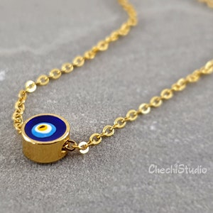 May include: A gold chain necklace with a blue and white evil eye charm. The charm is round and has a gold border.