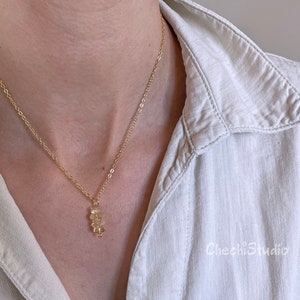 May include: A gold chain necklace with a small pendant made of multiple stacked, clear, faceted stones.