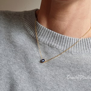 May include: A gold chain necklace with a small blue evil eye charm pendant.