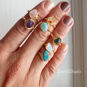 Puede incluir: Un conjunto de seis anillos de alambre dorado envueltos con diferentes piedras semipreciosas, incluyendo amatista, cuarzo rosa, turquesa, citrino, &oacute;palo y aventurina verde.