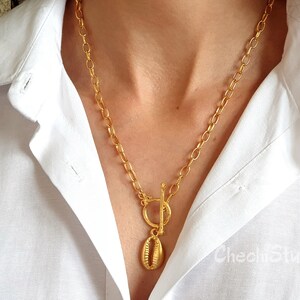 May include: A gold chain necklace with a gold seashell pendant and a toggle clasp.