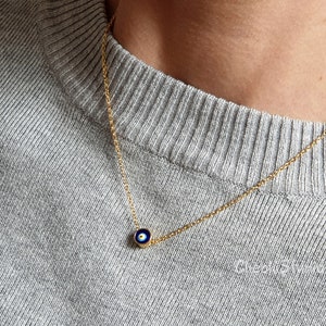 May include: A gold chain necklace with a small blue and white evil eye charm pendant.