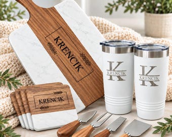 May include: A set featuring a white marble and wood serving board, four matching coasters, two white stainless steel tumblers, and four cheese knives with wooden handles. Each item is engraved with the name KRENCIC and wheat stalks.