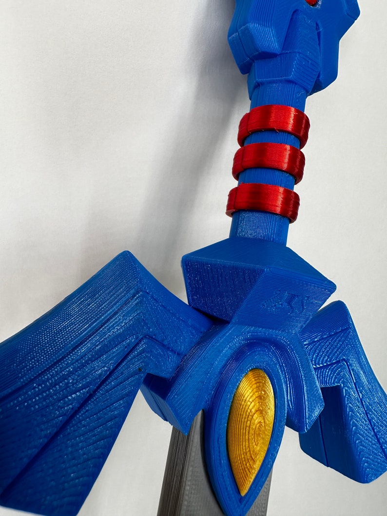 May include: A blue and gold 3D printed sword with red accents. The sword has a detailed design with a pointed tip and a handle with a textured surface.