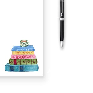 K&ouml;nnte beinhalten: Ein Stapel von f&uuml;nf bunten B&uuml;chern mit einer kleinen gr&uuml;n-wei&szlig;en Teetasse obenauf. Die B&uuml;cher sind pyramidenf&ouml;rmig angeordnet und haben verschiedene Muster und Designs auf ihren Einb&auml;nden.