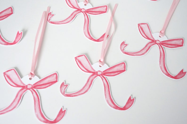 May include: Pink watercolour bow gift tags with white circles and pink ribbon.