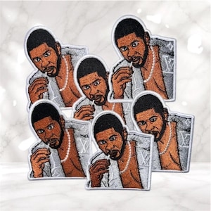 May include: Embroidered patches featuring a stylized illustration of a man with a beard, wearing a silver jacket and a pearl necklace. The patches have a white border and are arranged on a white surface.
