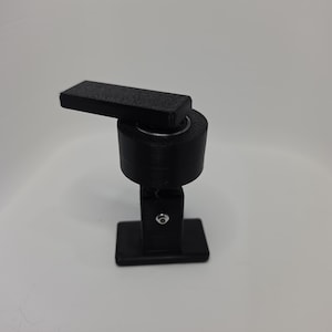 May include: A black, 3D-printed object with a rectangular base and a cylindrical body. A rectangular arm extends from the top, connected by a circular joint. The object is designed for a specific function, possibly as a tool or a component.