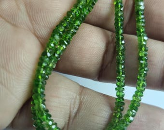 May include: A strand of small, faceted, vibrant green gemstone beads. The beads are uniform in size and shape, featuring a high-gloss finish that reflects light across their multiple cut surfaces, creating a sparkling, translucent appearance.