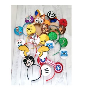 Può includere: Una collezione di fasce per capelli a tema personaggi colorati con vari personaggi dei cartoni animati, tra cui Topolino, Toy Story, Marvel e altro ancora.