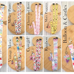 May include: A collection of eight fabric lanyards featuring various colorful patterns including Princess shape, Mickey Pants, Cherry and Bows, Mary Poppins, Vintage Movie, Cowgirl, Rainbow, and Balloon & Castles, each with a metal clasp and charm.