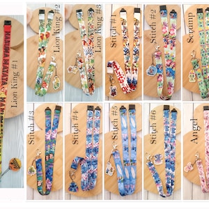 May include: A collection of eleven fabric lanyards featuring various character prints, including Lion King, Stitch, Scrump, and Angel designs. Each lanyard includes a metal lobster clasp and a matching character charm attached to the end.