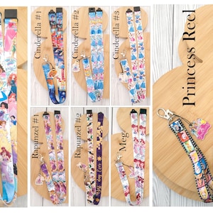 May include: A collection of fabric lanyards featuring various cartoon character prints and attached charms. The designs include Princess #1, Cinderella #1, #2, and #3, Rapunzel #1 and #2, Meg, and Princess Reel, each with distinct patterns and metal clips.
