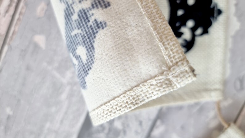 May include: Close-up of a white fabric bag with a blue and white patterned design. The bag has a white fabric trim around the edges.