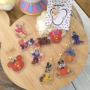 May include: A collection of Halloween-themed acrylic charms featuring Disney characters including Mickey, Minnie, Goofy, Pluto, Stitch, and Maleficent, some inside pumpkins, with a gold-tone lobster clasp and a display card reading Smile from Ear to Ear.