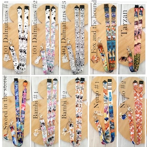 May include: A collection of ten fabric lanyards featuring various animated movie themes including 101 Dalmatians, Fox and the Hound, Tarzan, Sword in the Stone, Bambi, and Nemo, each equipped with a metal clasp and a matching character charm.