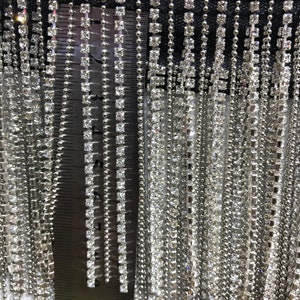 May include: Close-up of silver fringe trim with clear rhinestones. The fringe is approximately 11 inches long.
