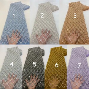 May include: Seven different colors of beaded lace fabric with a diamond pattern. The fabric is shown in the colors light blue, white, beige, silver, gray, gold, and lavender.