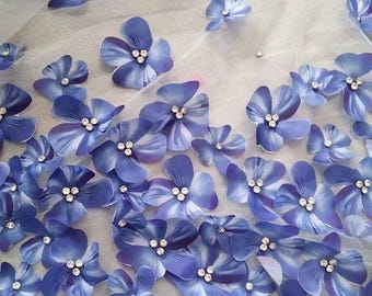 Puede incluir: Tela floral azul con flores 3D y pedrería. La tela es transparente y tiene una textura delicada.