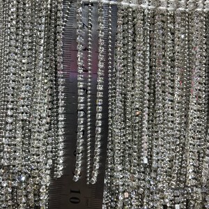 May include: Close-up of a silver trim with a fringe of clear rhinestones. A ruler is visible in the image, showing the trim is approximately 12 inches long.